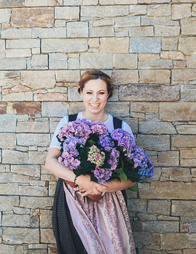 Tina Neudegger in Tracht mit Blumenstrauß vor dem 4*S Hotel Nesslerhof, Großarl